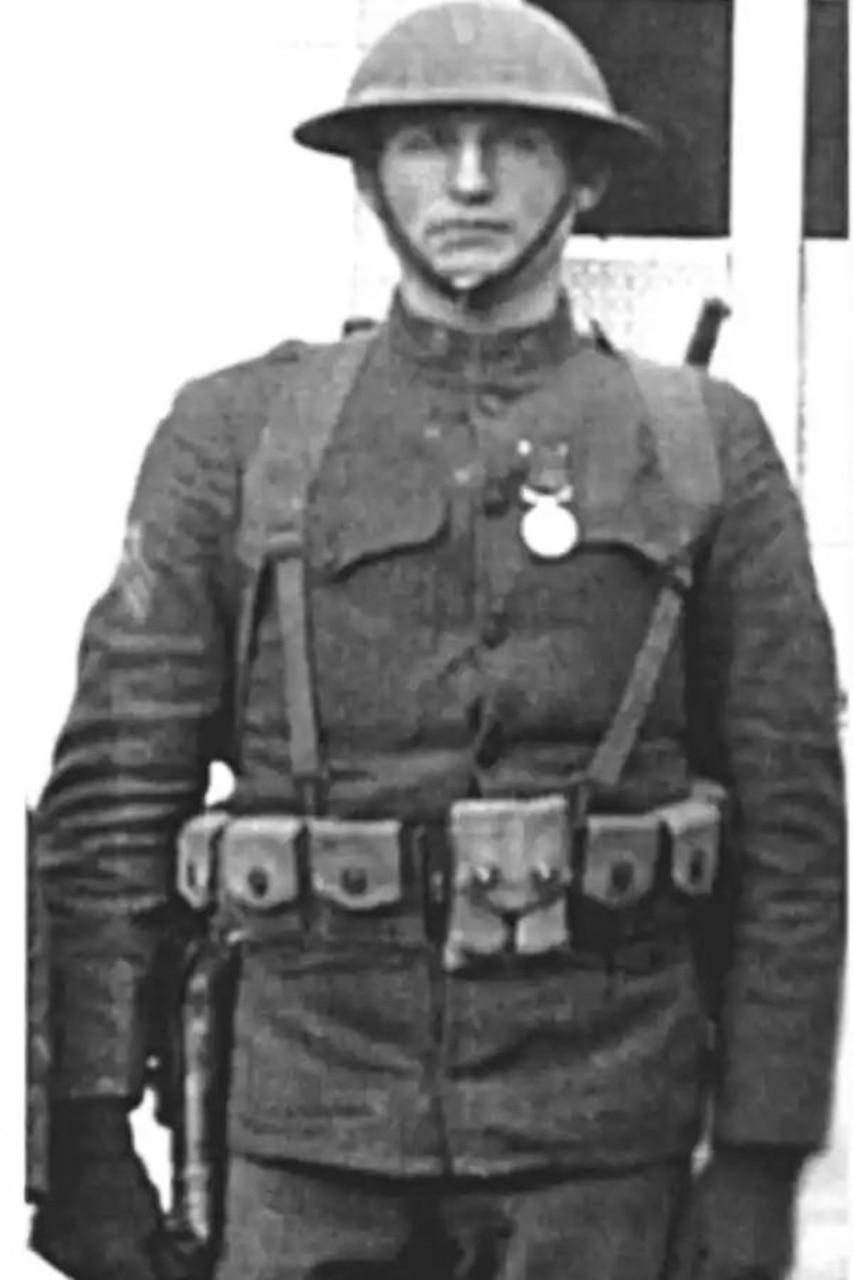 A man wearing a combat uniform stands at attention.
