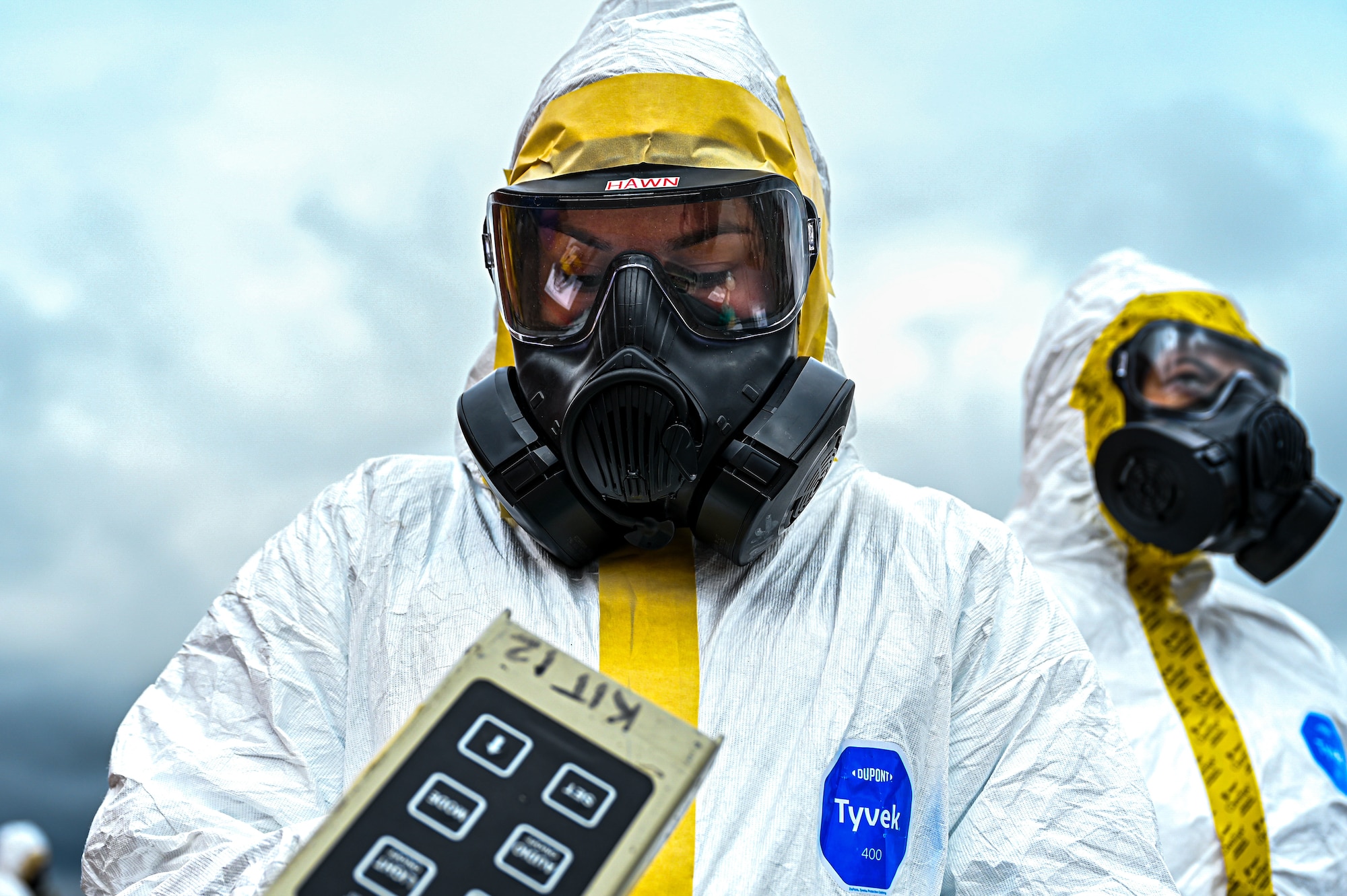 image of two Airmen in white hazmat suits and gas masks