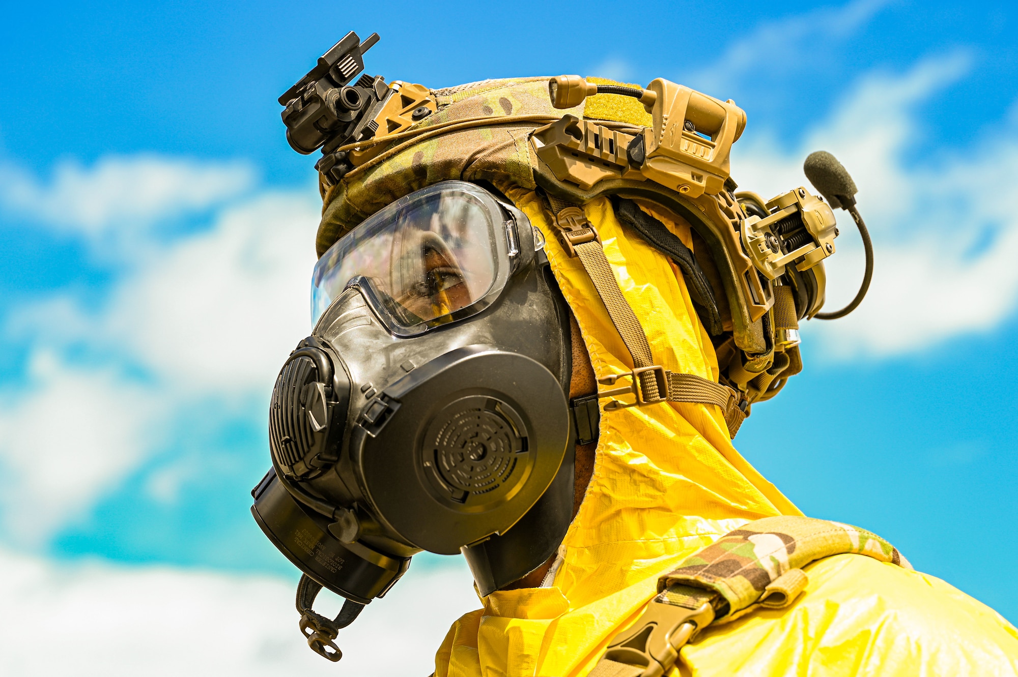 photo of an Airman in a yellow hazmat suit with a gas mask on