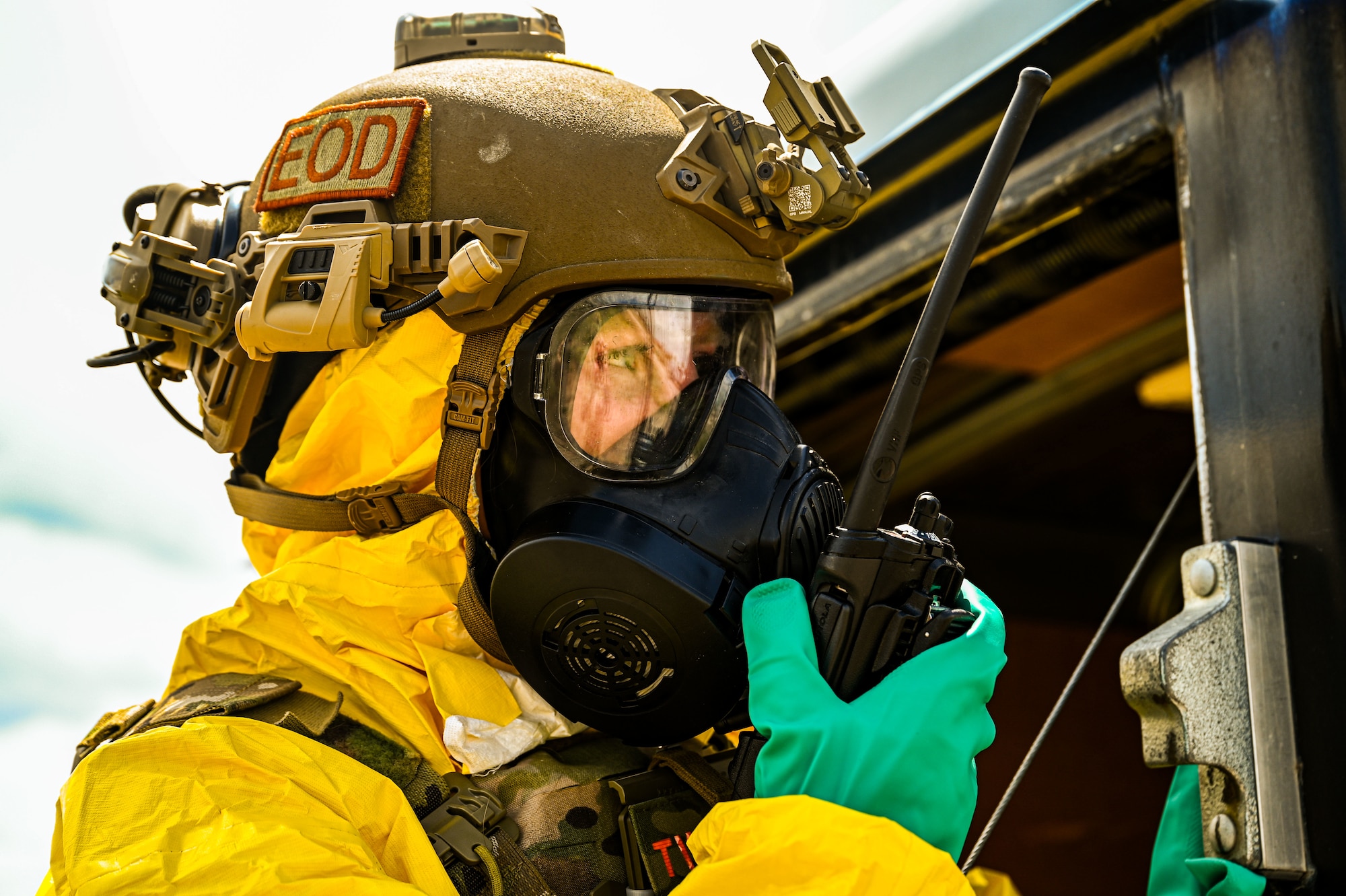 photo of an Airman in a yellow hazmat suit, speaking into a walkie-talkie