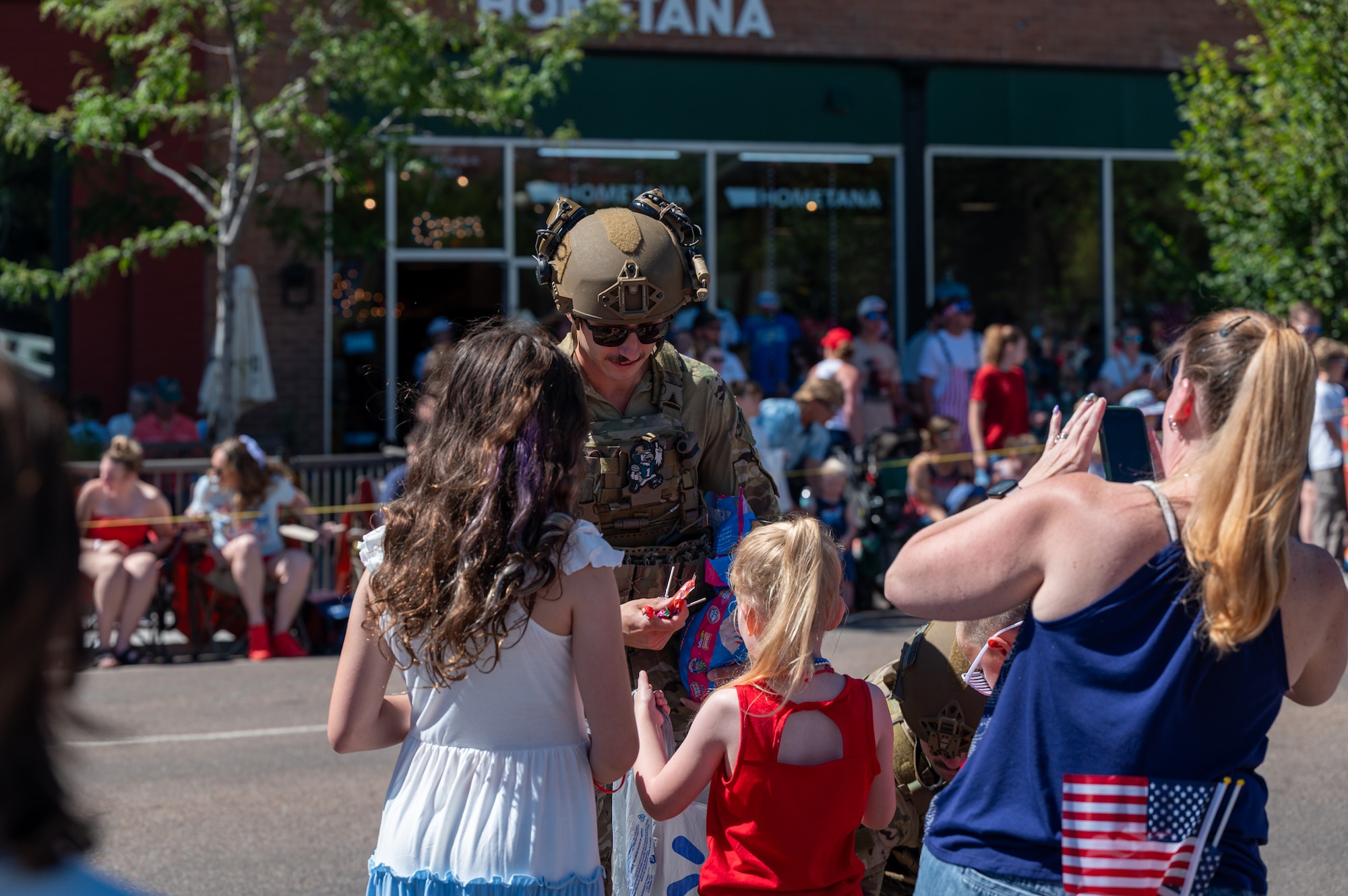 A uniformed man passes out candy to kids.