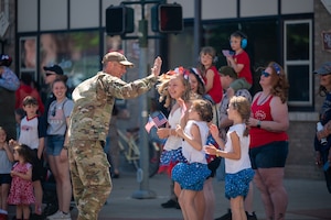 A uniformed man high-fives a group of children.