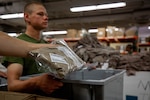 a uniform is placed in a bin held by a Marine recruit