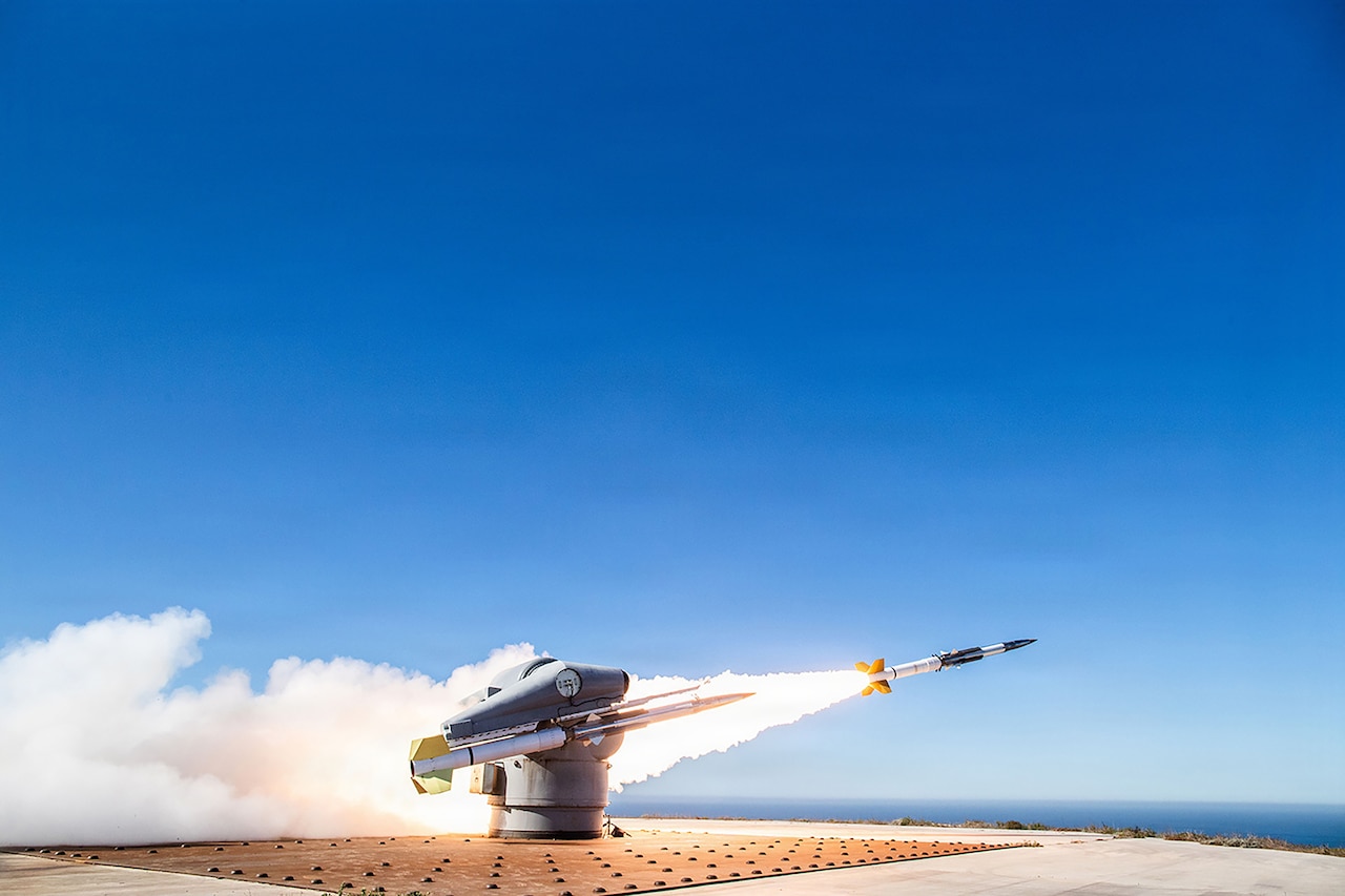 A rocket launcher fires a missile into the air as smoke shooting from the missile covers the ground.
