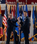 U.S. Air Force Col. George Chapman, incoming 91st Missile Wing (91st MW) commander, right, passes the 91st MW guidon to U.S. Air Force Maj. Gen. Stacy Jo Huser, 20th Air Force commander, left, during a change of command at Minot Air Force Base, North Dakota, July 8, 2026. The 91st MW is one of the Air Force's three operational missile units. The 91st MW maintains a fleet of Minuteman III intercontinental ballistic missiles and its mission is to defend the nation with a combat-ready nuclear force. (U.S. Air Force photo by Airman Benjamin Selchow)