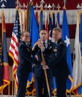 U.S. Air Force Col. James Schlabach, outgoing 91st Missile Wing (91st MW) commander, right, receives the 91st MW guidon from U.S. Air Force Maj. Gen. Stacy Jo Huser, 20th Air Force commander, left, assuming command of the 91st MW during a change of command ceremony at Minot Air Force Base, North Dakota, July 8, 2026. Schlabach reflected on the accomplishments of the 91st MW, praising the Airmen and staff that worked under his command for their dedication and work towards the mission of global deterrence. (U.S. Air Force photo by Airman Benjamin Selchow)
