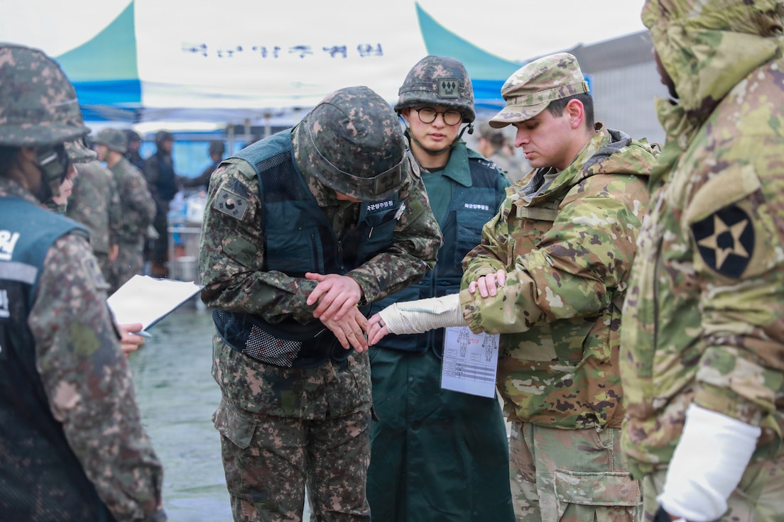 A U.S. Army soldier, acting as a simulated casualty with a sprained wrist, is evaluated by Republic of Korea Army nursing officers at Deokjeong Station, South Korea, during the Dragon Lift evacuation exercise.