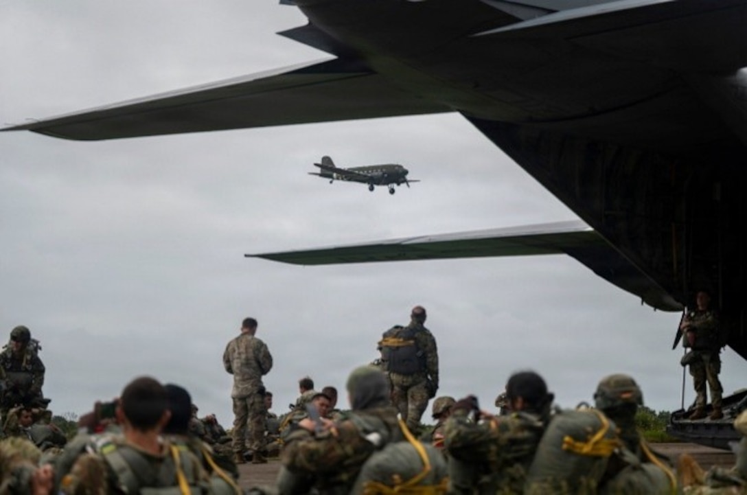 Paratroopers from the U.S. Army, Air Force and Allied forces prepare parachutes on a flightline at Cherbourg, France, June 7, 2026. The event honored the 82nd and 101st Airborne Divisions and Allied forces who participated in Operation Overlord on June 6, 1944.
