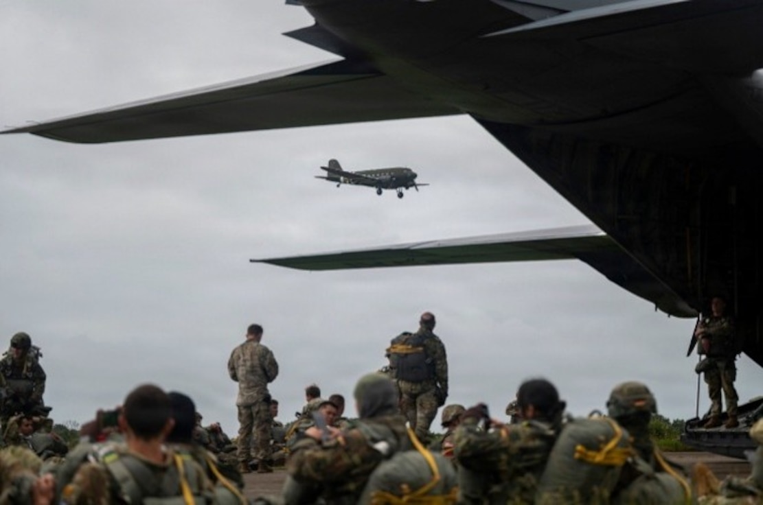 Paratroopers from the U.S. Army, Air Force and Allied forces prepare parachutes on a flightline at Cherbourg, France, June 7, 2026. The event honored the 82nd and 101st Airborne Divisions and Allied forces who participated in Operation Overlord on June 6, 1944.