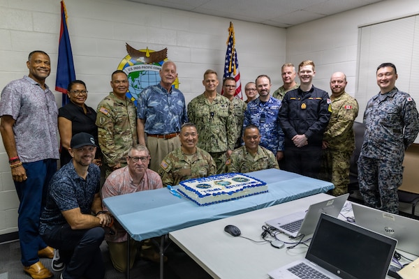 U.S. Navy Rear Adm. Josh Lasky, Commander, Joint Task Force-Micronesia, Dr. John Wood, U.S. Pacific Command’s J7 Training and Exercises Deputy Director, military leaders, and support personnel celebrate the opening of the Pacific Multi-Domain Training and Experimentation Capability Forward - Guam facility following a ribbon-cutting ceremony at Building 4175 on U.S. Naval Base Guam, June 22, 2026.