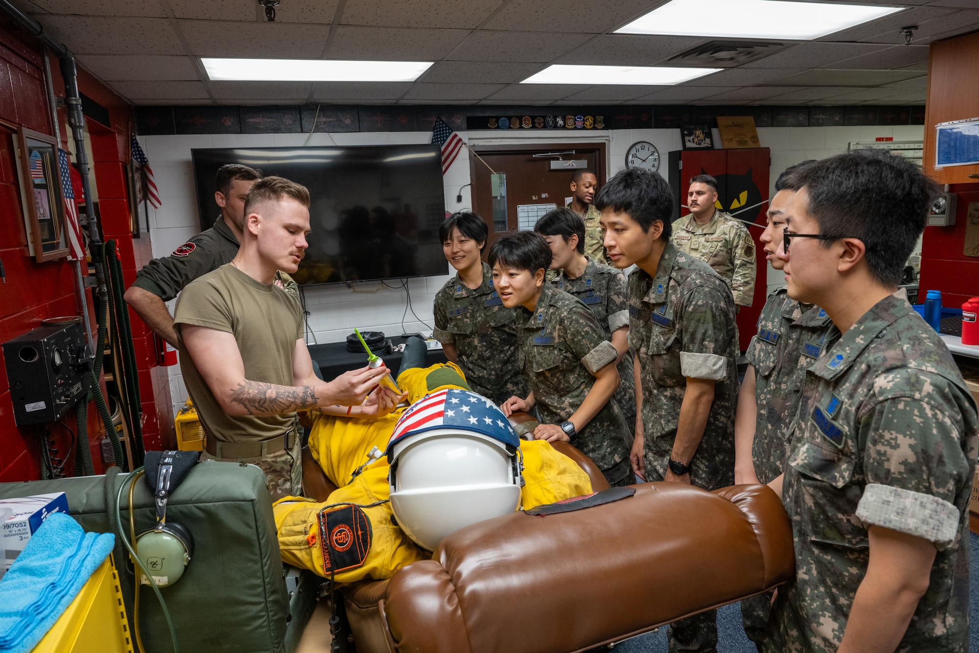 An Airman shows a pressurized flight suit to ROKAF Airmen.