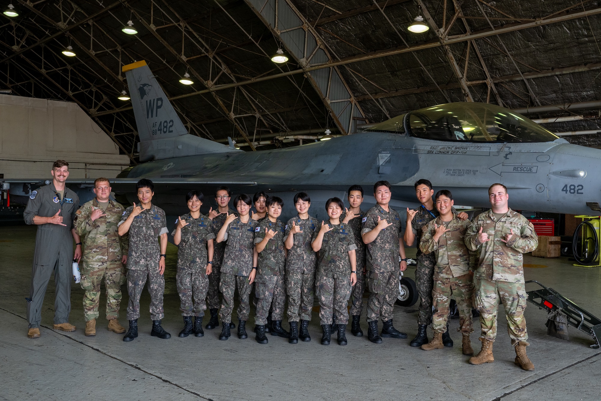 U.S. Air Force Airmen and ROKAF Airmen pose for a group photo in front of an aircraft.