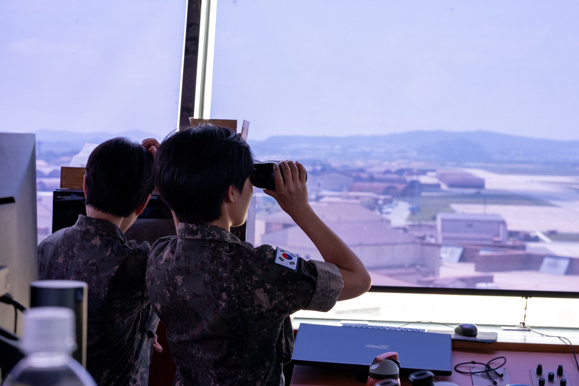 A ROKAF translation officer uses binoculars to look out of an air traffic control tower.