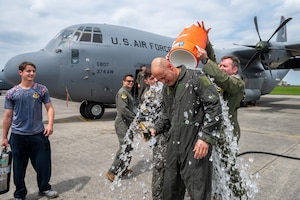Airmen dump a bucket of ice water on another Airman.