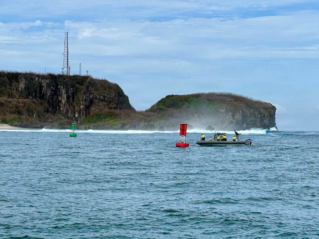 U.S. Navy Explosive Ordnance Disposal Mobile Unit Five personnel work to free Buoy 2 so it can be relocated from the center of the channel entrance at Outer Apra Harbor, Guam, on July 9, 2026. U.S. Coast Guard Forces Micronesia/Sector Guam, Station Apra Harbor, and U.S. Navy Explosive Ordnance Disposal Mobile Unit Five personnel worked together to remove Buoy 2, which moved off station during the storm into the channel, where vessels expect safe water. (U.S. Coast Guard photo by Chief Petty Officer Neil Rice)
