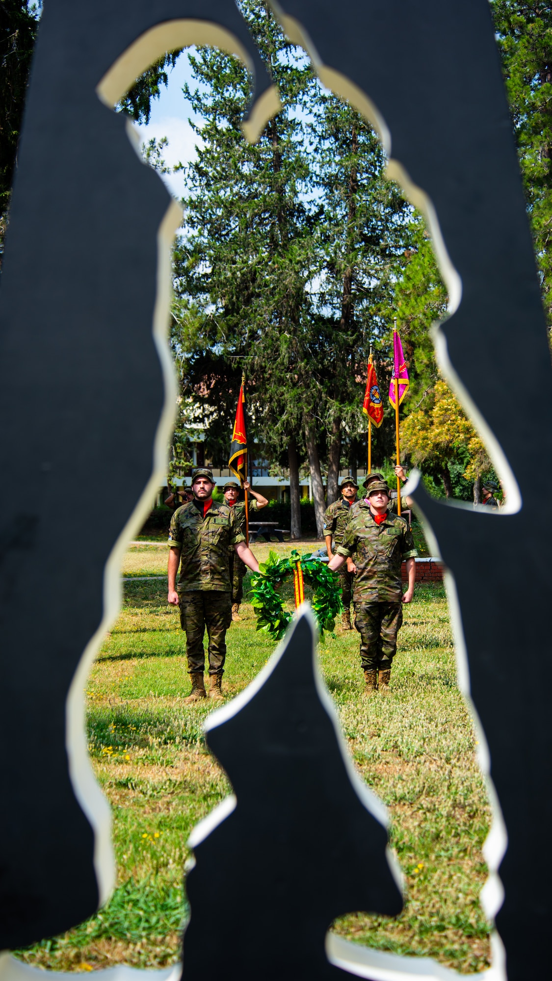 Spanish army members assigned to the Spanish Patriot Unit carry a ceremonial wreath toward a memorial.