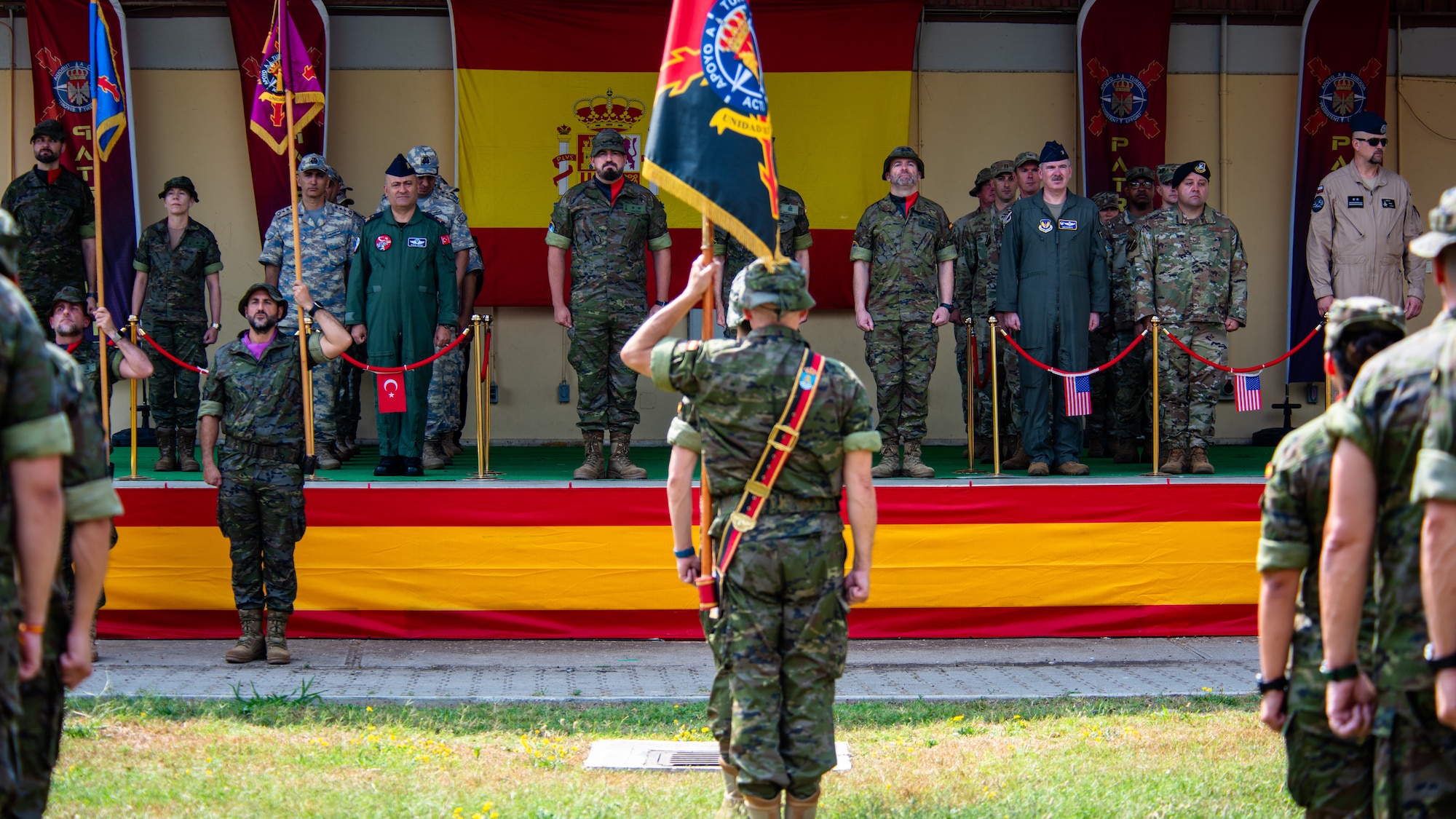 Spanish army members assigned to the Spanish Patriot Unit stand in formation with a unit guidon.