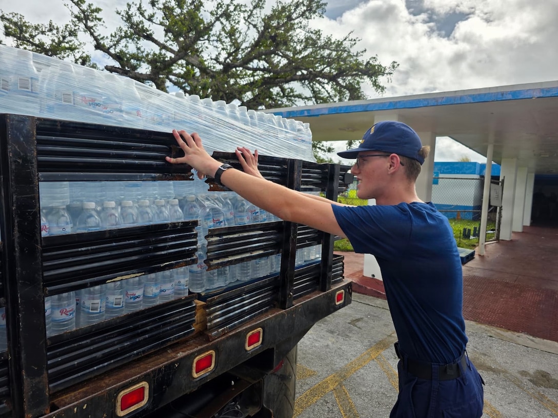 Personnel from U.S. Coast Guard Base Guam and Forces Micronesia/Sector Guam coordinate with the community in Guam to transport pallets of water to a U.S. Coast Guard HC-130J Hercules airplane from Air Station Barbers Point in concert with planned damage assessments of Rota in the Northern Mariana Islands, on July 9, 2026. U.S. Coast Guard crews continue to assess and rectify discrepancies to aids to navigation, waterways, and channel conditions across the Marianas following Super Typhoon Bavi. (U.S. Coast Guard photo by Senior Chief Petty Officer Kevin Reilly)