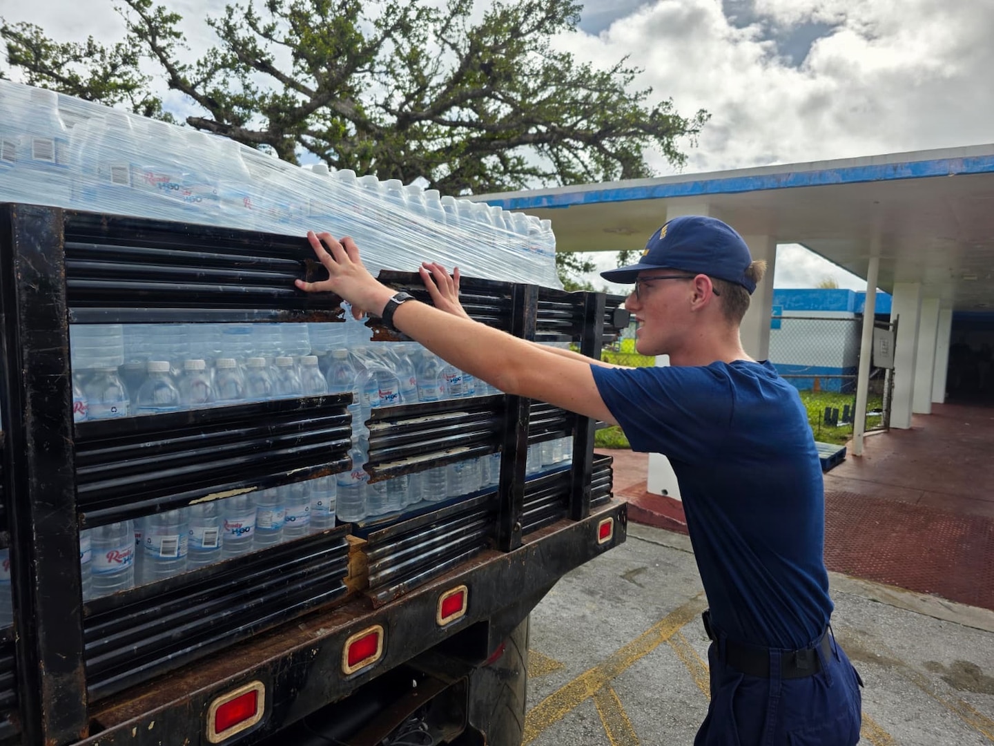 Personnel from U.S. Coast Guard Base Guam and Forces Micronesia/Sector Guam coordinate with the community in Guam to transport pallets of water to a U.S. Coast Guard HC-130J Hercules airplane from Air Station Barbers Point in concert with planned damage assessments of Rota in the Northern Mariana Islands, on July 9, 2026. U.S. Coast Guard crews continue to assess and rectify discrepancies to aids to navigation, waterways, and channel conditions across the Marianas following Super Typhoon Bavi. (U.S. Coast Guard photo by Senior Chief Petty Officer Kevin Reilly)