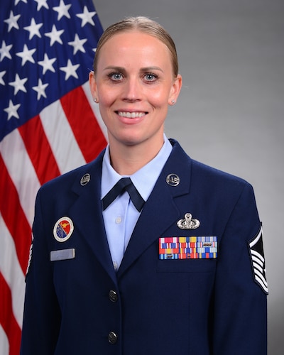 Female in uniform posing with U.S. flag.