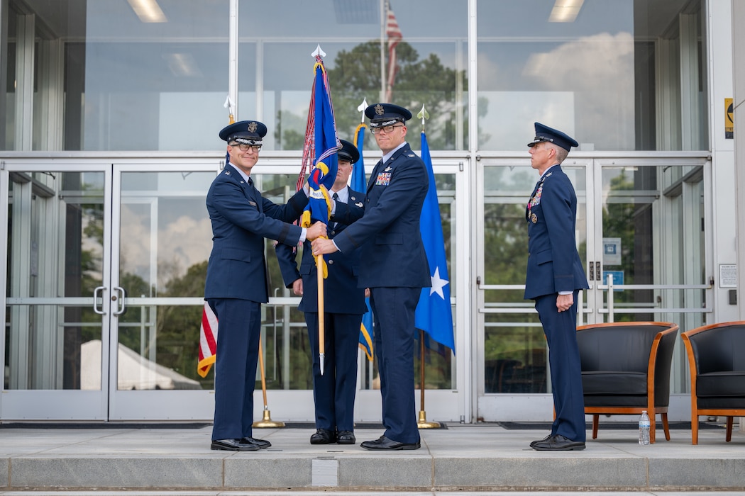 Col. Wayne Dirkes, second from right, accepts the guidon from Air Force Test Center Commander Maj. Gen. Scott Cain, left, to assume command of Arnold Engineering Development Complex during a June 27, 2026, Change of Command ceremony at Arnold Air Force Base, Tenn., headquarters of AEDC. The ceremony took place during the AEDC 75th anniversary open house celebration held on the same date at Arnold AFB. Prior to his latest assignment, Dirkes commanded the 704th Test Group, a unit of AEDC headquartered at Holloman Air Force Base, N.M. Also pictured are outgoing AEDC Commander Col. Grant Mizell, right, and AEDC Senior Enlisted Leader Chief Master Sgt. Evan McCoy. (U.S. Air Force photo by Keith Thornburgh)