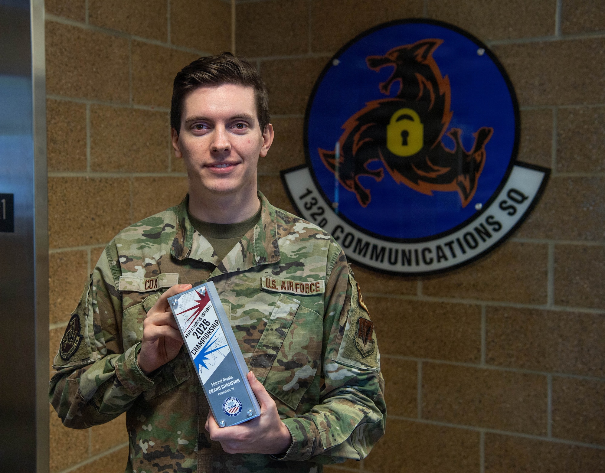 Uniformed Air Force male stands holding gaming trophy