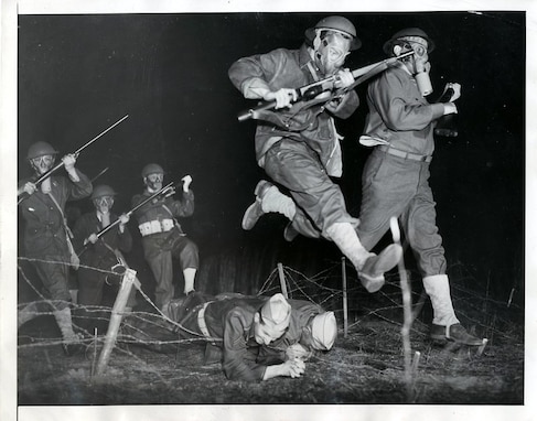 ATLANTA, Feb. 23, 1943 – Neither U.S. Rangers or British Commandos are these troops, but they advance through barbed wire in the best ranger-commando style. They’re part-time soldiers of the Georgia State Guard, and their training has made them plenty tough. The two soldiers lying prone on the wire are holding it down while their comrades advance over the bridge of their backs.