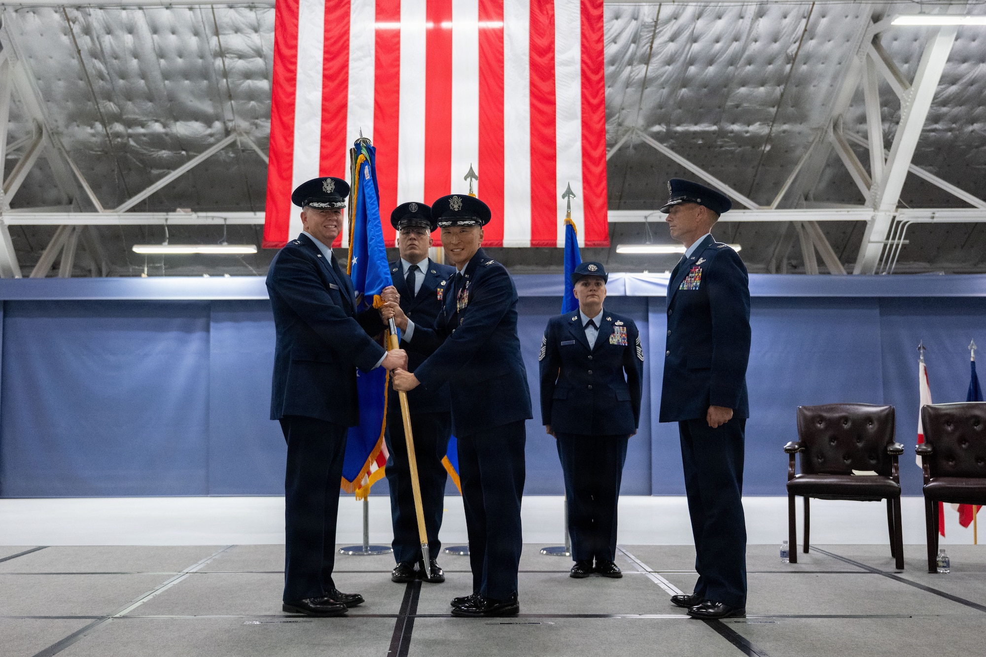 Officers hold a guidon on a stage.