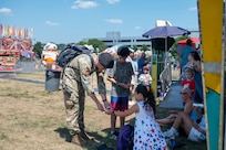 U.S. Air Force Tech. Sgt. Brian Walker, drone preventative officer with the 11th Security Forces Squadron, hands out stickers during Freedom Fest at Joint Base Anacostia-Bolling, Washington, D.C., July 4, 2026. The three-day event featured carnival rides, food trucks and a variety of games and activities to celebrate the nation’s historic birthday. (U.S Air Force photo by Senior Airman Shanel Toussaint)