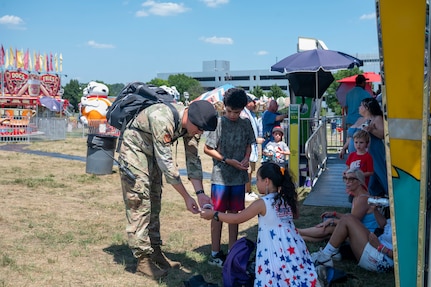 U.S. Air Force Tech. Sgt. Brian Walker, drone preventative officer with the 11th Security Forces Squadron, hands out stickers during Freedom Fest at Joint Base Anacostia-Bolling, Washington, D.C., July 4, 2026. The three-day event featured carnival rides, food trucks and a variety of games and activities to celebrate the nation’s historic birthday. (U.S Air Force photo by Senior Airman Shanel Toussaint)
