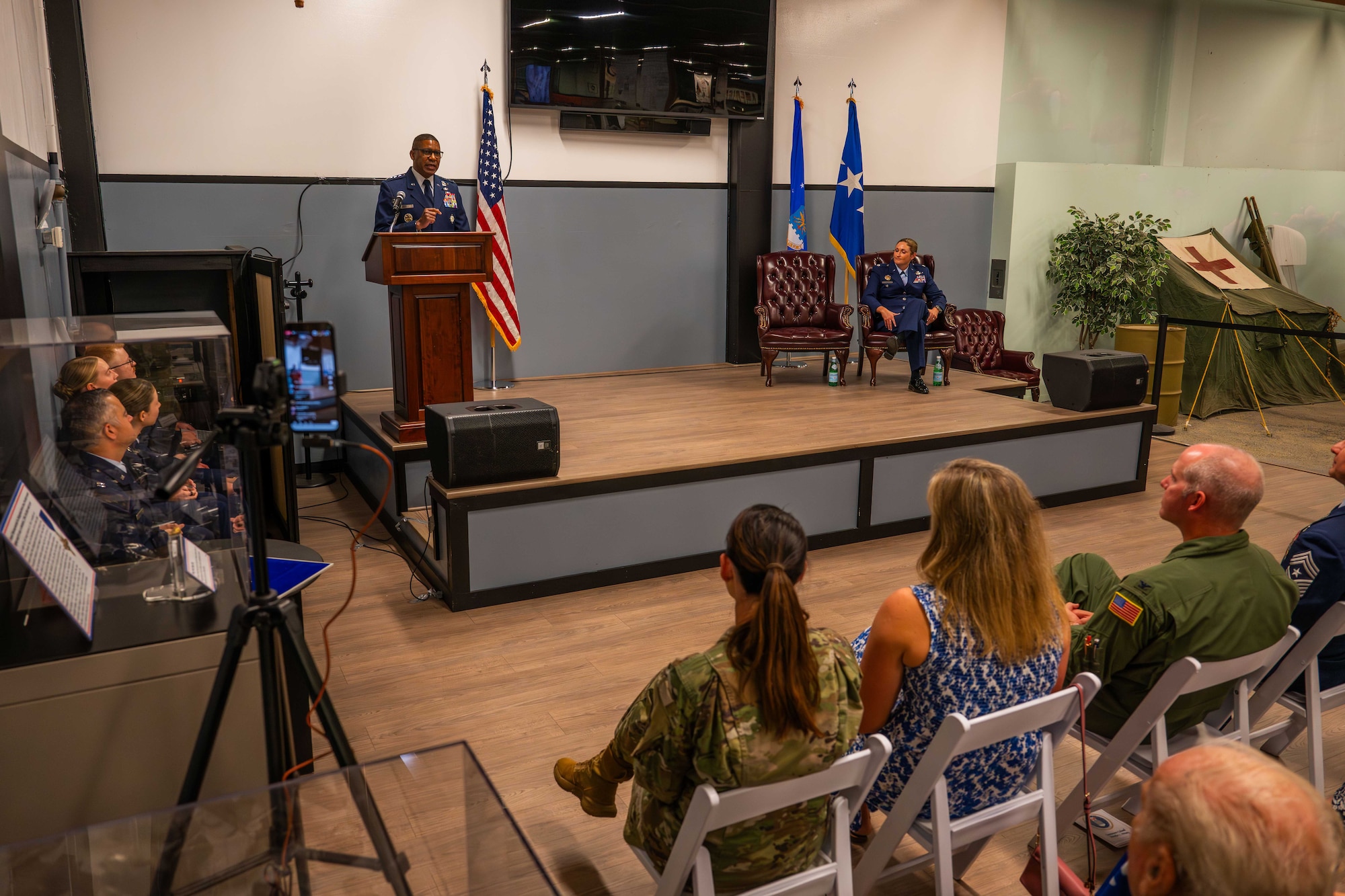 A U.S. Air Force General officer speaks at a podium in front of a crowd during a ceremony indoors.