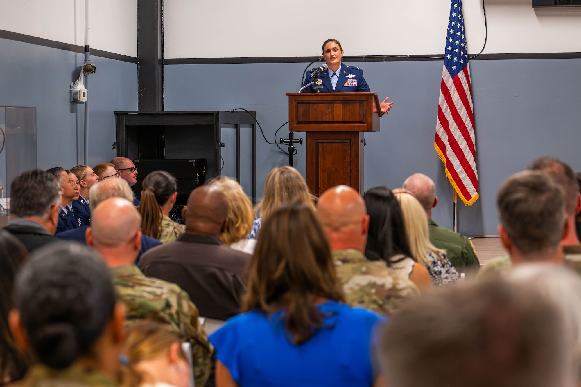 a newly promoted Air Force colonel speaks at a podium in front of an audience.