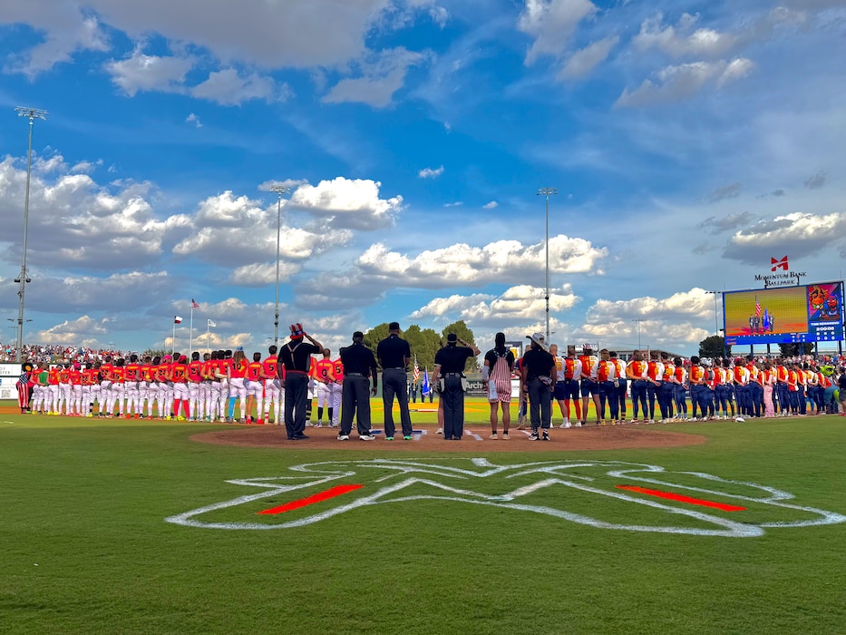 Photo focused on base honor guard in the middle of two teams lined up during the national anthem