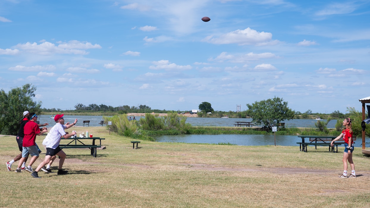 People are playing frisbee outdoors by a lake