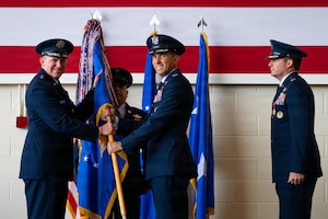 U.S. Air Force Maj. Gen. Charles Bolton, Eighteenth Air Force commander, left, passes the 317th Airlift Wing guidon to Col. Christopher Welch, incoming commander, during a change of command ceremony at Dyess Air Force Base, Texas, July 8, 2026. The passing of the guidon is a historic military tradition that symbolizes the official transfer of command, responsibility and authority from the outgoing to the incoming commander. (U.S. Air Force photo by Senior Airman Jade M. Caldwell)
