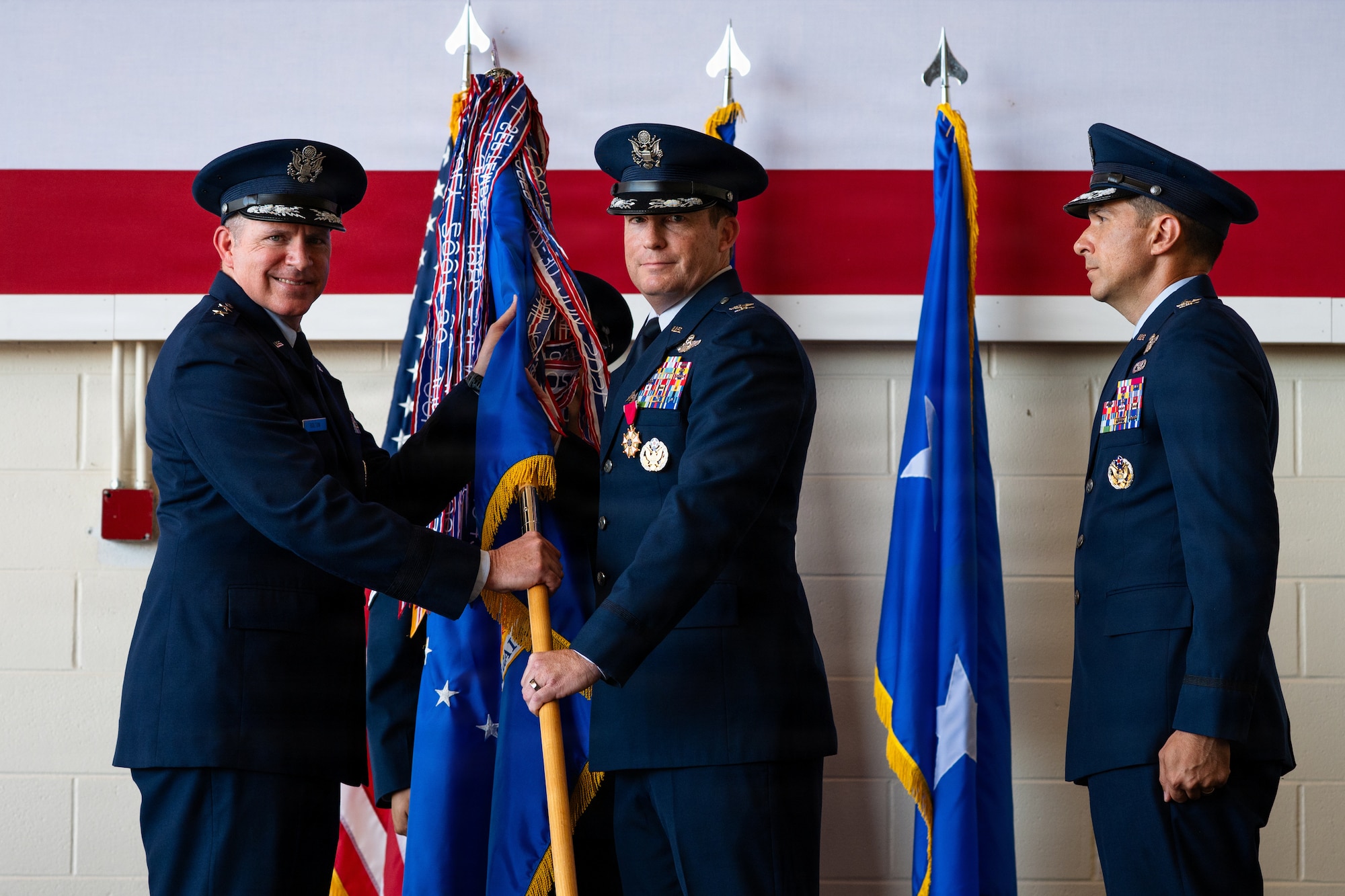 U.S. Air Force Col. Justin Diehl, outgoing 317th Airlift Wing commander, center, passes the 317th AW guidon to Maj. Gen. Charles Bolton, Eighteenth Air Force commander, during a change of command ceremony at Dyess Air Force Base, Texas, July 8, 2026. The passing of the guidon is a historic military tradition symbolizing the official transfer of command, responsibility and authority from the outgoing to the incoming commander. (U.S. Air Force photo by Senior Airman Jade M. Caldwell)