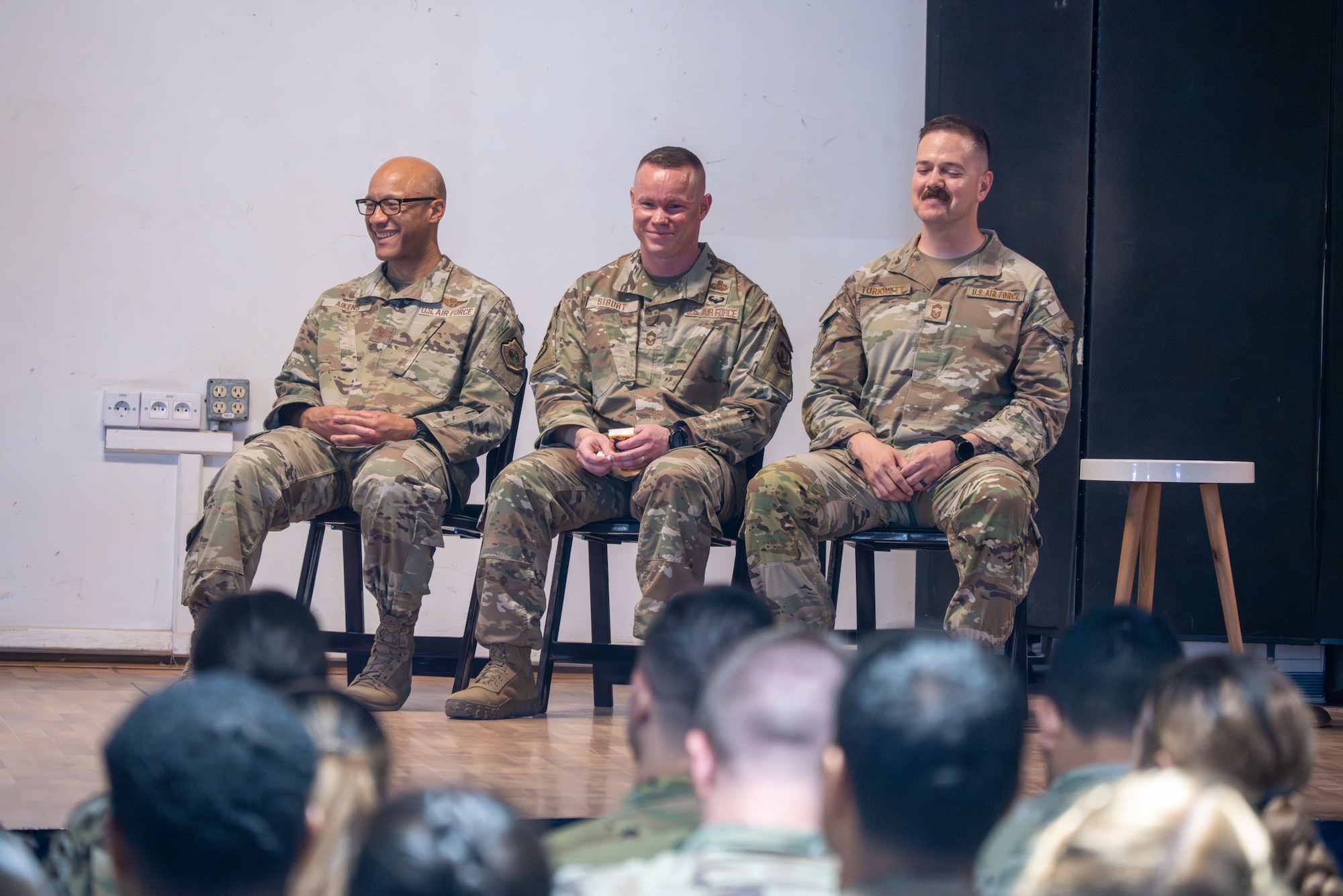 U.S. Air Force Col. Kris Aikens, 449th Air Expeditionary Group commander, left, U.S. Air Force Chief Master Sgt. Nicholas Siburt, 449th AEG outgoing senior enlisted leader, center, and U.S. Air Force Chief Master Sgt. Christopher Turknett, 449th AEG inbound senior enlisted leader, right, sit on stage during the Group Change of Responsibility ceremony at Camp Lemonnier, June 18, 2026. The 449th AEG serves as the Joint Air Component Coordination Element to Combined Joint Task Force-Horn of Africa and in partnership with joint, interagency, intergovernmental, and multinational teammates, the 449th AEG also engages in theater security cooperation activities. (U.S. Air Force photo by Senior Airman Luis Gomez)