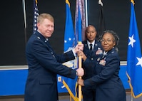 Brig. Gen. Gwendolyn A. Foster (right), relinquishes the guidon to Maj. Gen. (Dr.) Robert K. Bogart is the Director, Defense Health Network Central, and Commander, Medical Readiness Command Alpha (left) at the 59th MDW change of command ceremony at Joint Base San Antonio-Lackland on July 8, 2026.