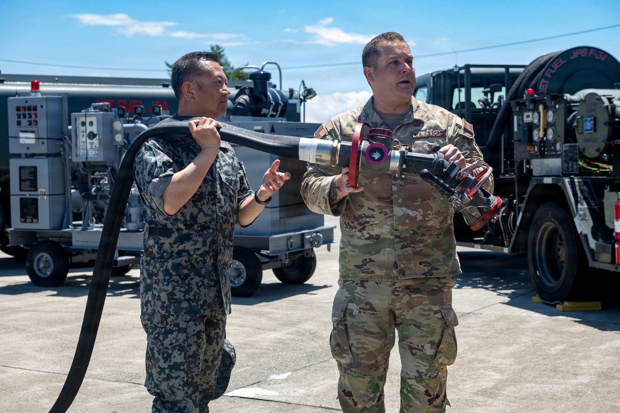 U.S. Air Force Tech. Sgt. Mark Goddard, right, 35th Logistic Readiness Squadron noncommissioned officer in charge of fuel knowledge operations, demonstrates how to use a fueling hose to Japan Air Self-Defense Force Maj. Gen. Teru Tomikawa, 3rd Air Wing (AW) commander.