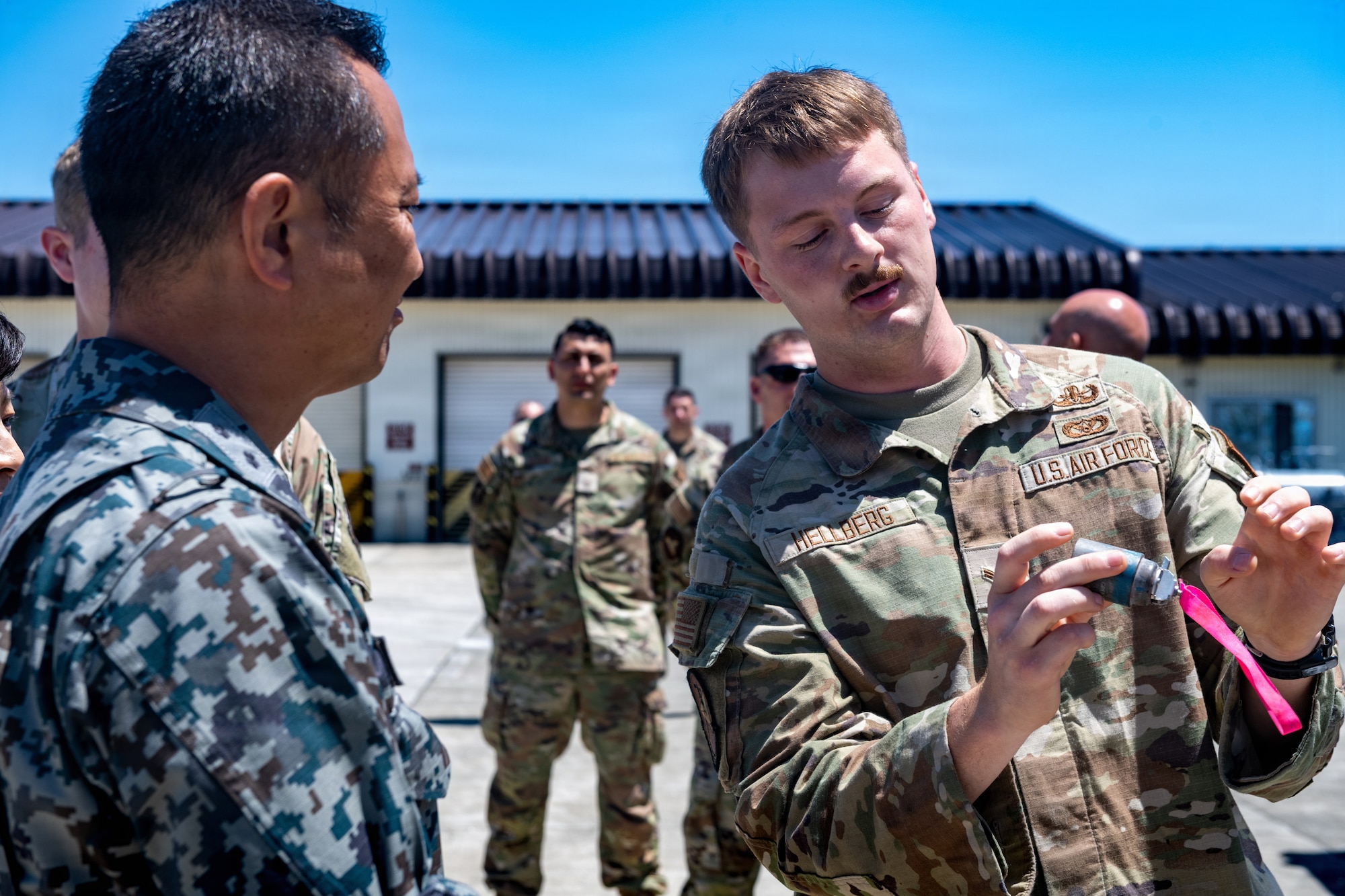 U.S. Air Force Airman 1st Class Andrew Hellberg, 35th Civil Engineer Squadron explosive ordnance disposal team member, demonstrates a grenade training aid to Japan Air Self-Defense Force Maj. Gen. Teru Tomikawa, 3rd Air Wing (AW) commander.