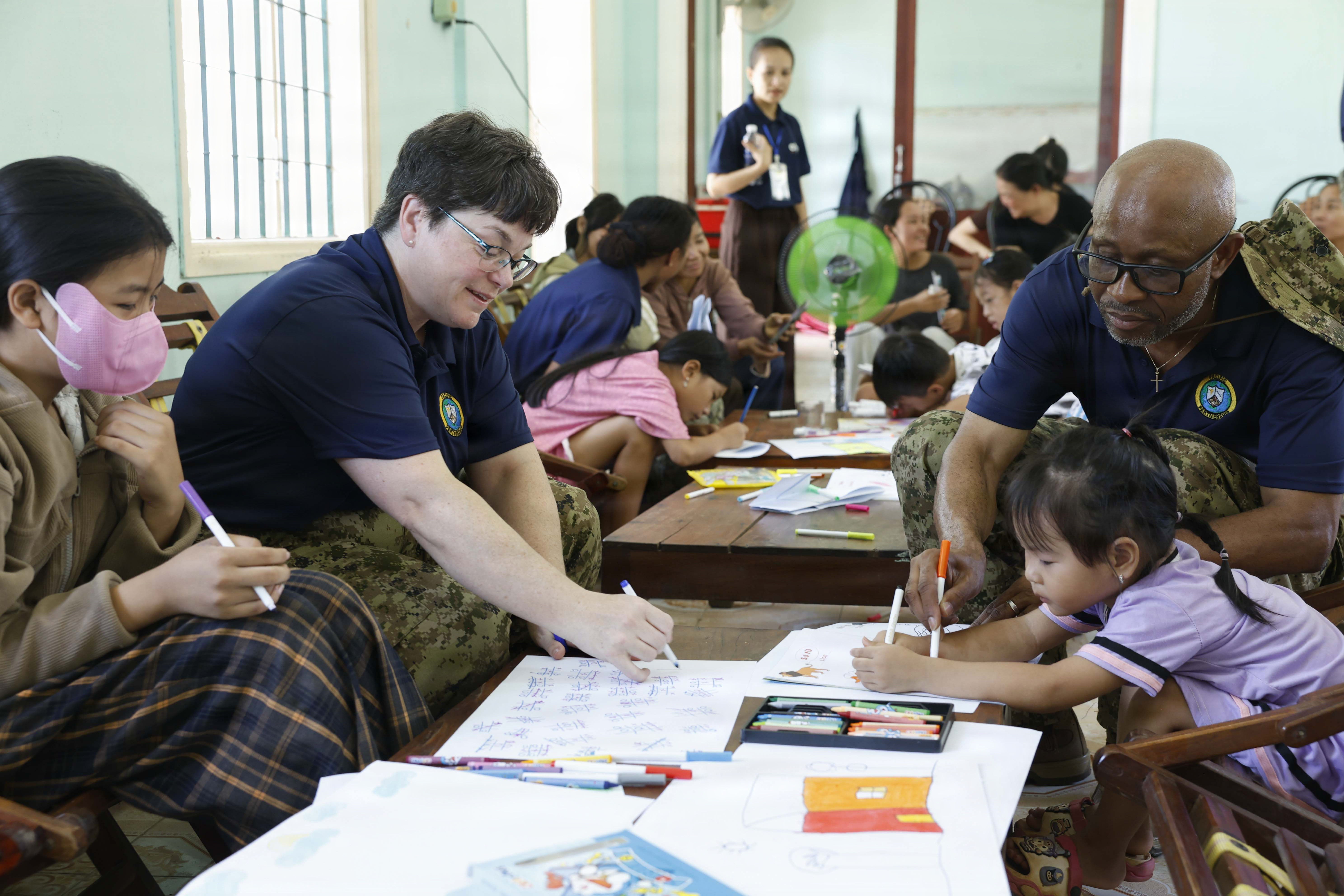 Canadian Armed Forces Cmdr. Genevieve Chatelois, left, and Canadian Armed Forces Maj. Innocent Inienwe, assigned to Pacific Partnership 2026 (PP26), draw pictures with children during a PP26 community outreach and engagement event at the Gio Linh Center for Rehabilitation of Children with Disabilities in Quang Tri, Vietnam, June 24, 2026.