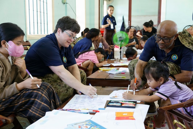 Canadian Armed Forces Cmdr. Genevieve Chatelois, left, and Canadian Armed Forces Maj. Innocent Inienwe, assigned to Pacific Partnership 2026 (PP26), draw pictures with children during a PP26 community outreach and engagement event at the Gio Linh Center for Rehabilitation of Children with Disabilities in Quang Tri, Vietnam, June 24, 2026.