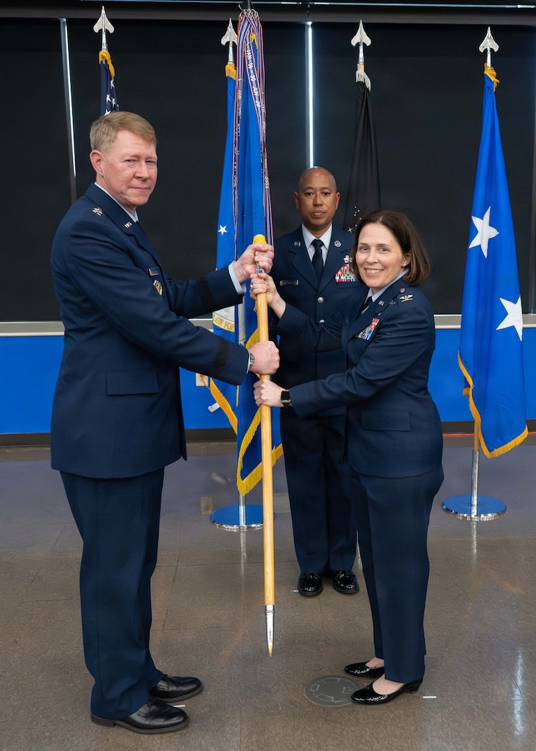Maj. Gen. (Dr.) Robert K. Bogart, Director, Defense Health Network Central, and Commander, Medical Readiness Command Alpha, (right) passes the guidon to Col. Tracy Bozung, 59th Medical Wing commander, at the 59th MDW change of command ceremony at Joint Base San Antonio-Lackland on July 8, 2026.