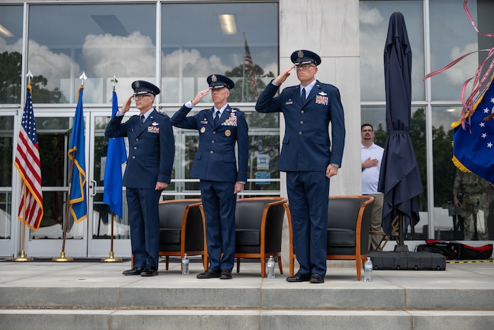 Air Force Test Center Commander Maj. Gen. Scott Cain, left, outgoing Arnold Engineering Development Complex Commander Col. Grant Mizell, center, and incoming AEDC Commander Col. Wayne Dirkes salute while the national anthem is performed prior to the AEDC Change of Command ceremony that took place June 27, 2026, as part of the AEDC 75th anniversary open house celebration at Arnold Air Force Base, Tenn., headquarters of AEDC. Outgoing AEDC Commander Col. Grant Mizell relinquished command of the Complex to incoming Commander Col. Wayne Dirkes. (U.S. Air Force photo by Keith Thornburgh)