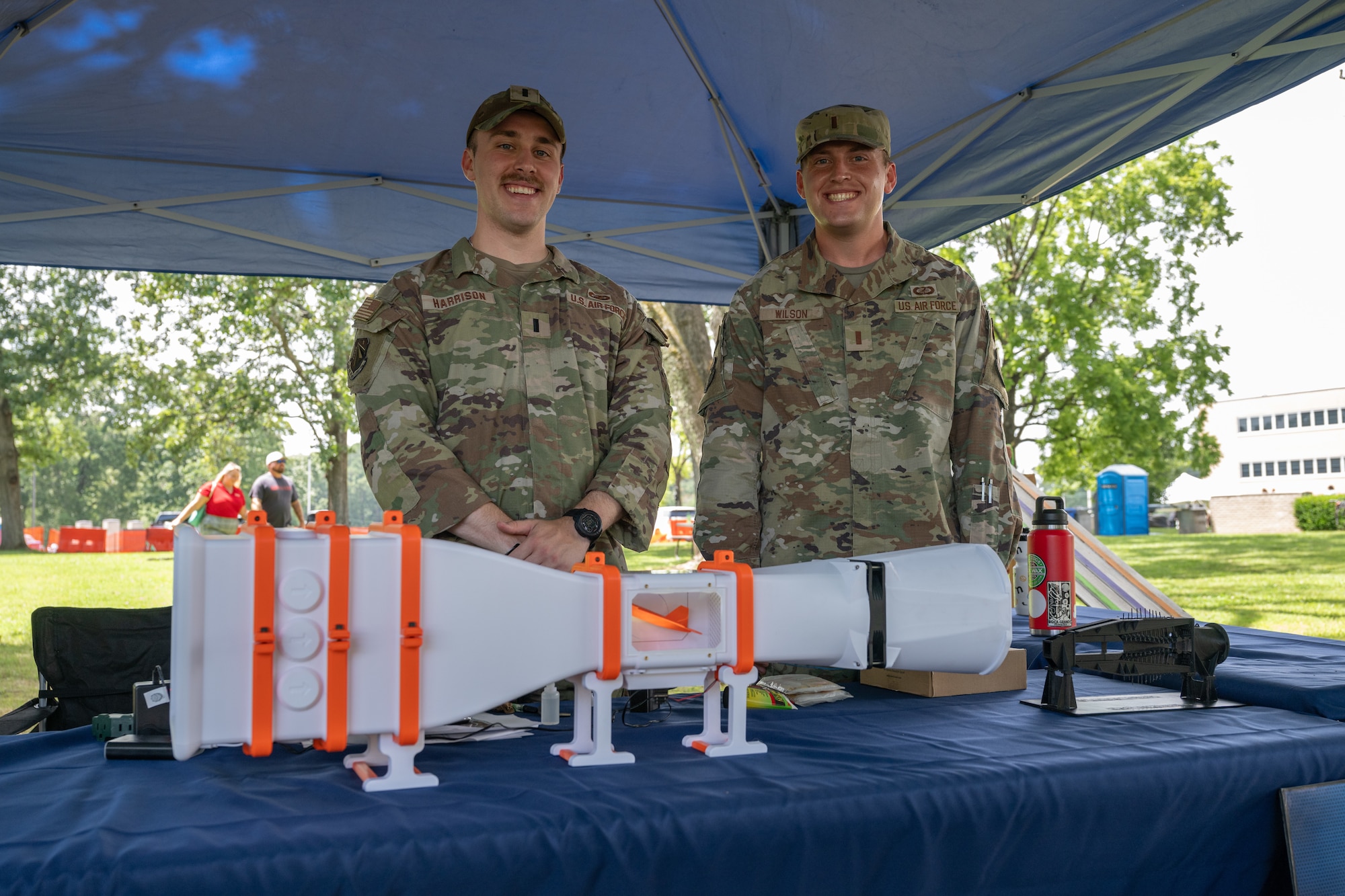 1st Lt. John Harrison, left, and 2nd Lt. Troy Wilson with the Air Force Research Laboratory High Speed Aerodynamics Branch pose for a photo behind a wind tunnel model during the Arnold Engineering Development Complex 75th anniversary open house celebration June 27, 2026, at Arnold Air Force Base, Tenn., headquarters of AEDC. The public open house was held to coincide with the original June 25, 1951, dedication of AEDC. The history and accomplishments of AEDC throughout its first 75 years were showcased during the open house. (U.S. Air Force photo by Keith Thornburgh)