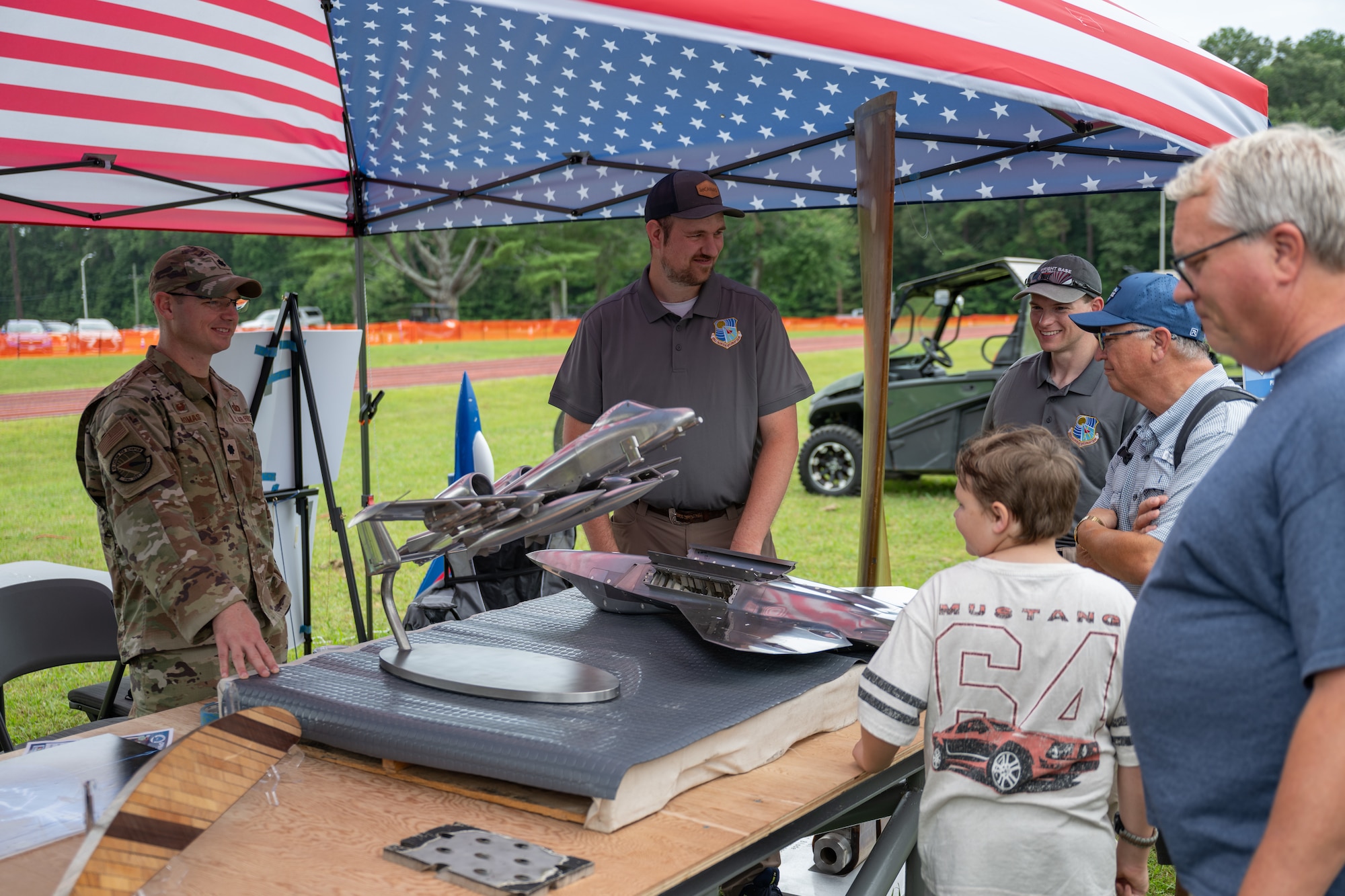 Lt. Col. Jason Thomas, commander of the 716th Test Squadron, left, and other members of the 716 TS team, discuss aircraft testing models on display during the Arnold Engineering Development Complex 75th anniversary open house celebration June 27, 2026, at Arnold Air Force Base, Tenn., headquarters of AEDC. The public open house was held to coincide with the original June 25, 1951, dedication of AEDC. The history and accomplishments of AEDC throughout its first 75 years were showcased during the open house. (U.S. Air Force photo by Keith Thornburgh)