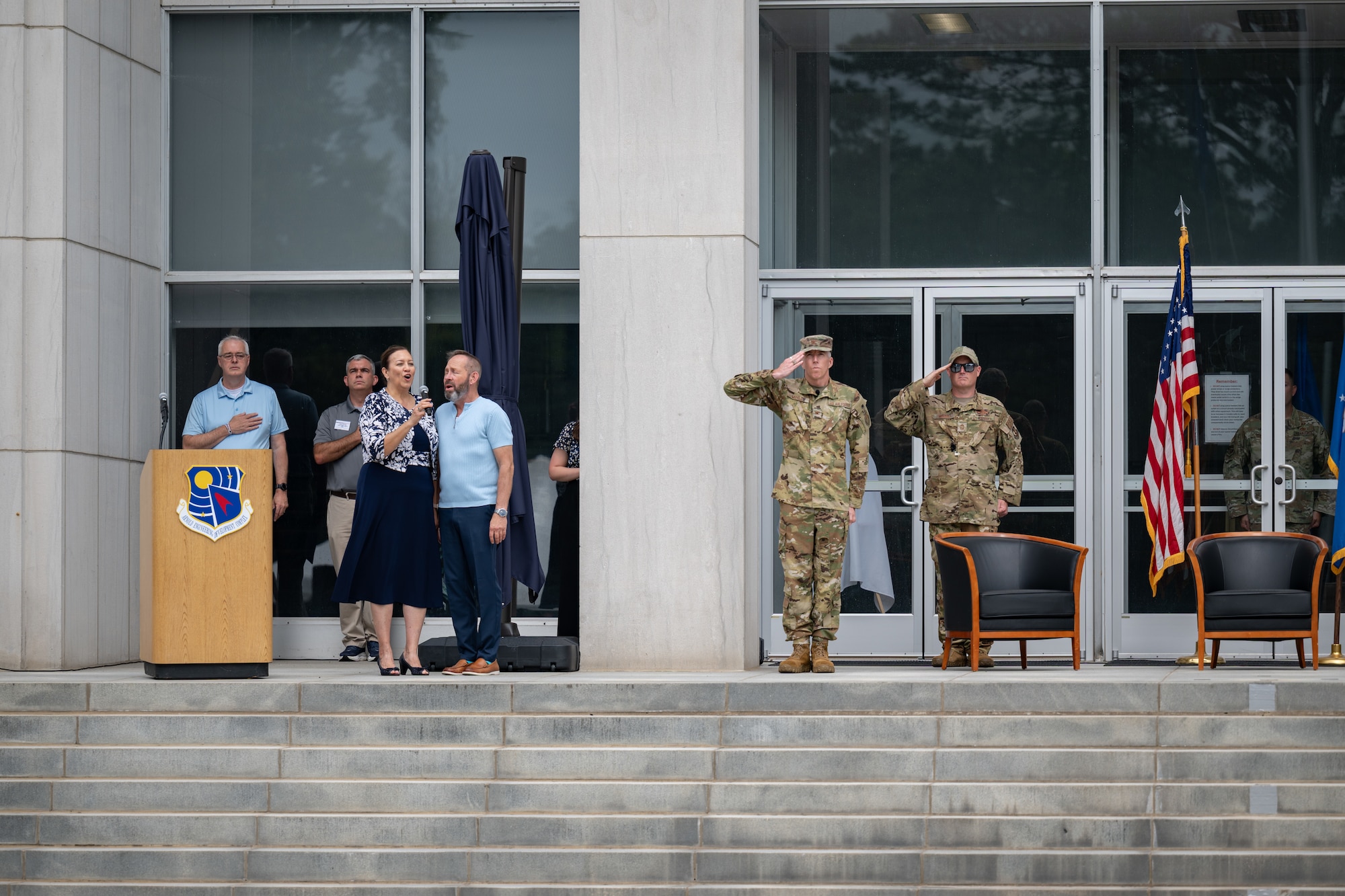 Kimberly Heng and J.D. Dill perform the national anthem to officially kick off the Arnold Engineering Development Complex 75th anniversary open house celebration June 27, 2026, at Arnold Air Force Base, Tenn., headquarters of AEDC. The public open house was held to coincide with the original June 25, 1951, dedication of AEDC. Also pictured, from left, are Tullahoma Mayor Lynn Sebourn, AEDC Public Affairs Chief Jason Austin, outgoing AEDC Commander Col. Grant Mizell and AEDC Senior Enlisted Leader Chief Master Sgt. Evan McCoy. (U.S. Air Force photo by Keith Thornburgh)