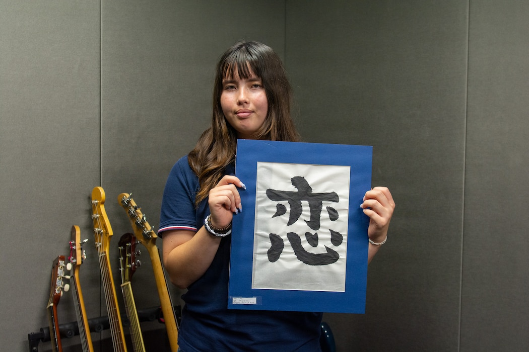 Riley M. holds her award-winning artwork, "Koi" at the Commander, Fleet Activities Works Yokosuka Teen Center June 9, 2026. Her piece, created using traditional Japanese calligraphy, earned national recognition in the Boys & Girls Clubs of America’s 2025-26 National Arts Contest