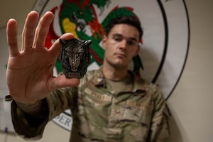 U.S. Air Force Senior Airman Brandon Pratt, 8th Maintenance Group commander’s support staff supervisor, holds a commander’s coin he received for being selected as the Wolf Pack’s "Pride of the Pack" at Kunsan Air Base, Republic of Korea, July 9, 2026. Pratt was selected for the week of July 6-10 due to his career achievements and his impact on the base's readiness and well-being. (U.S. Air Force photo by Senior Airman Tabatha Chapman)