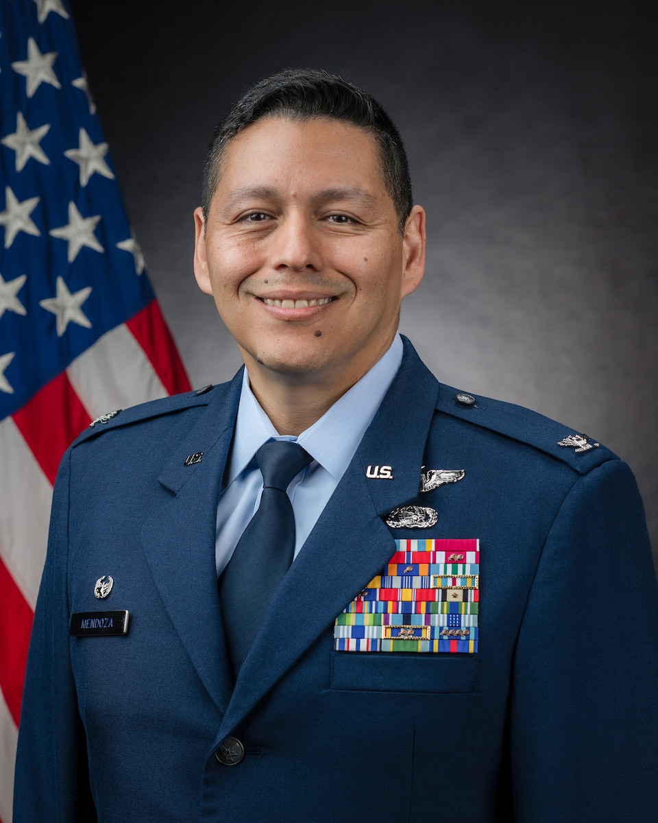 An Airman poses for a photo in front of an American flag.